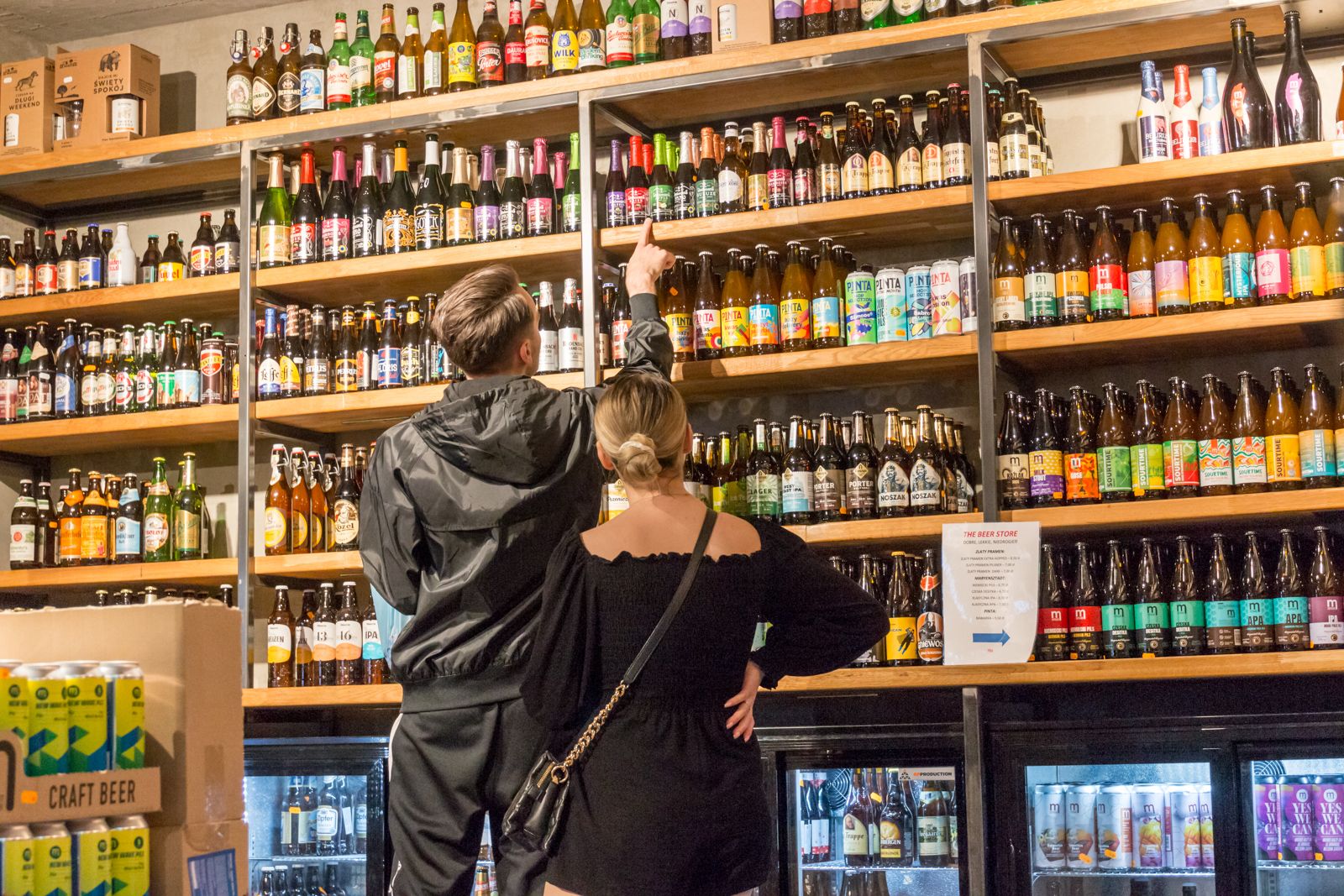 Goście wybierają piwo przy regale z setkami butelek w The Beer Store