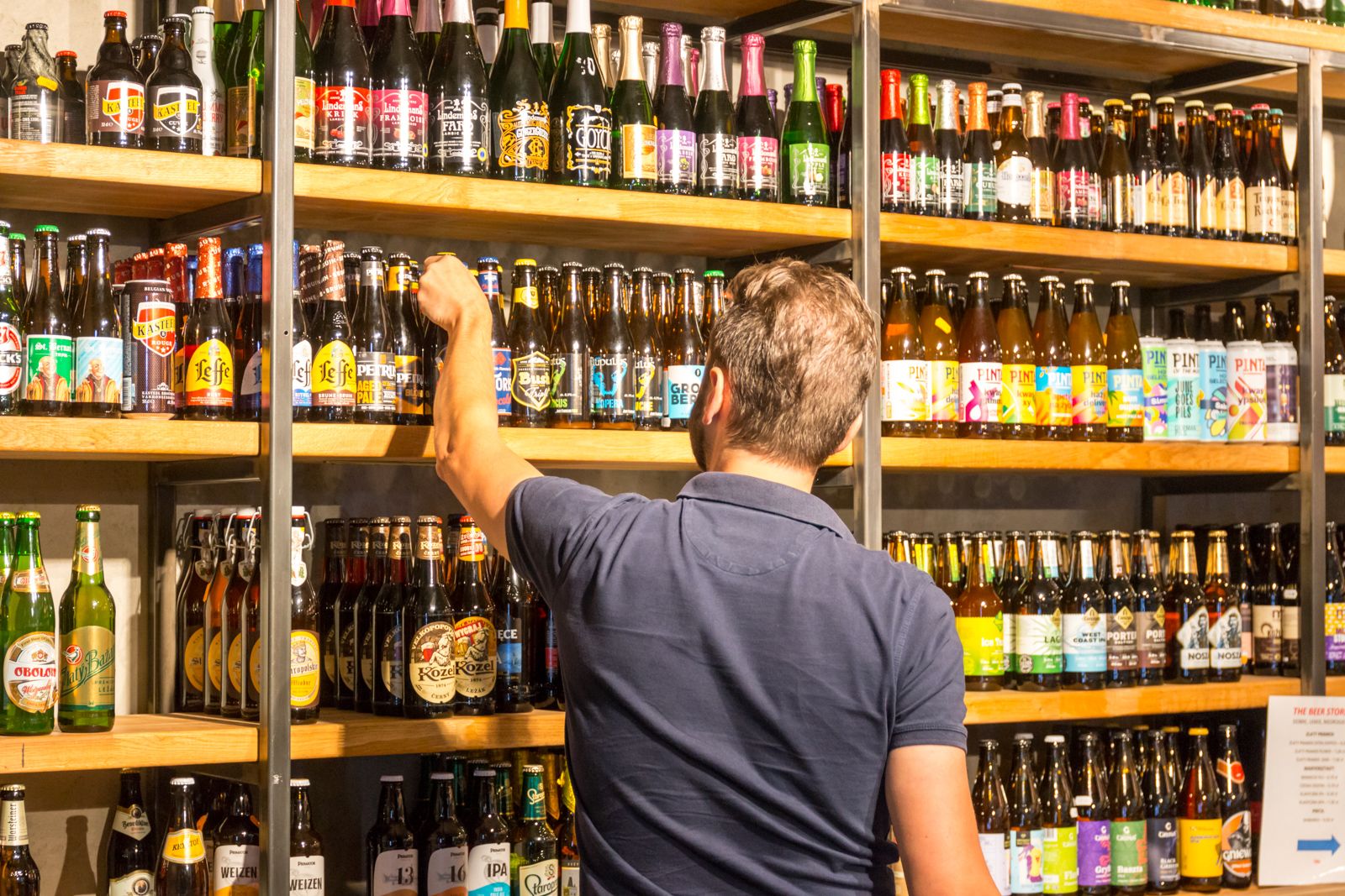 Klient sięga po butelkę z regału z piwami w The Beer Store