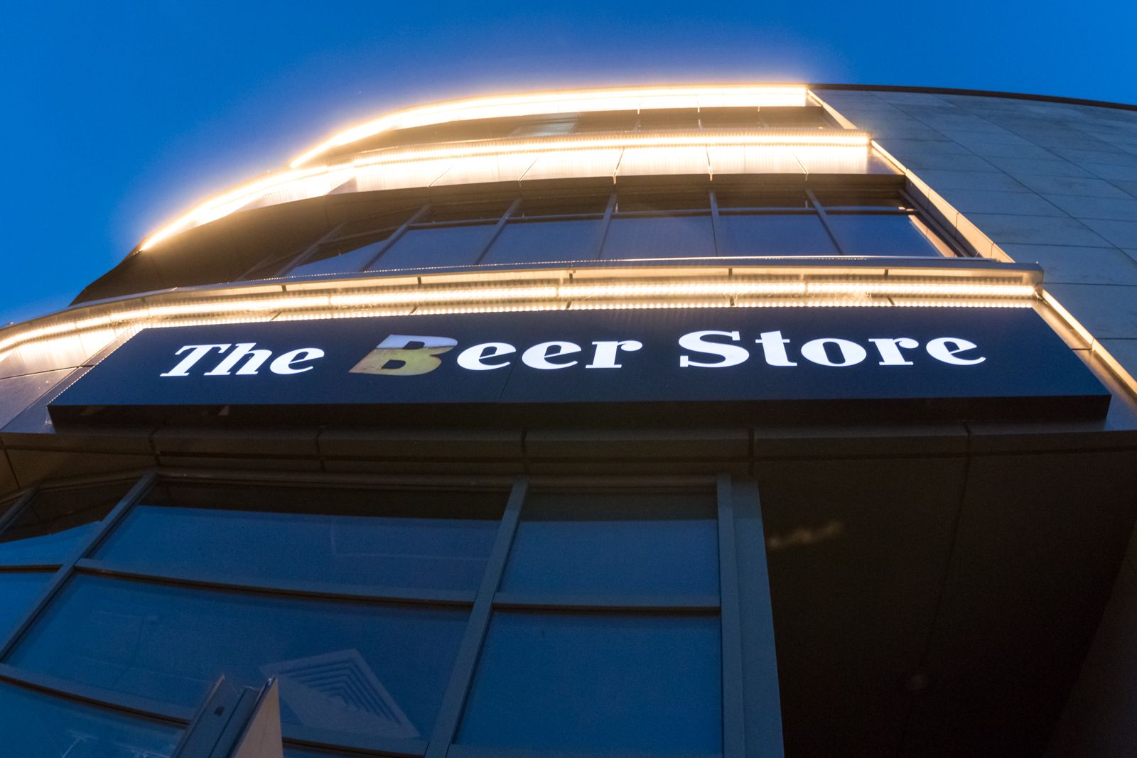 Podświetlany szyld The Beer Store na budynku wieczorem